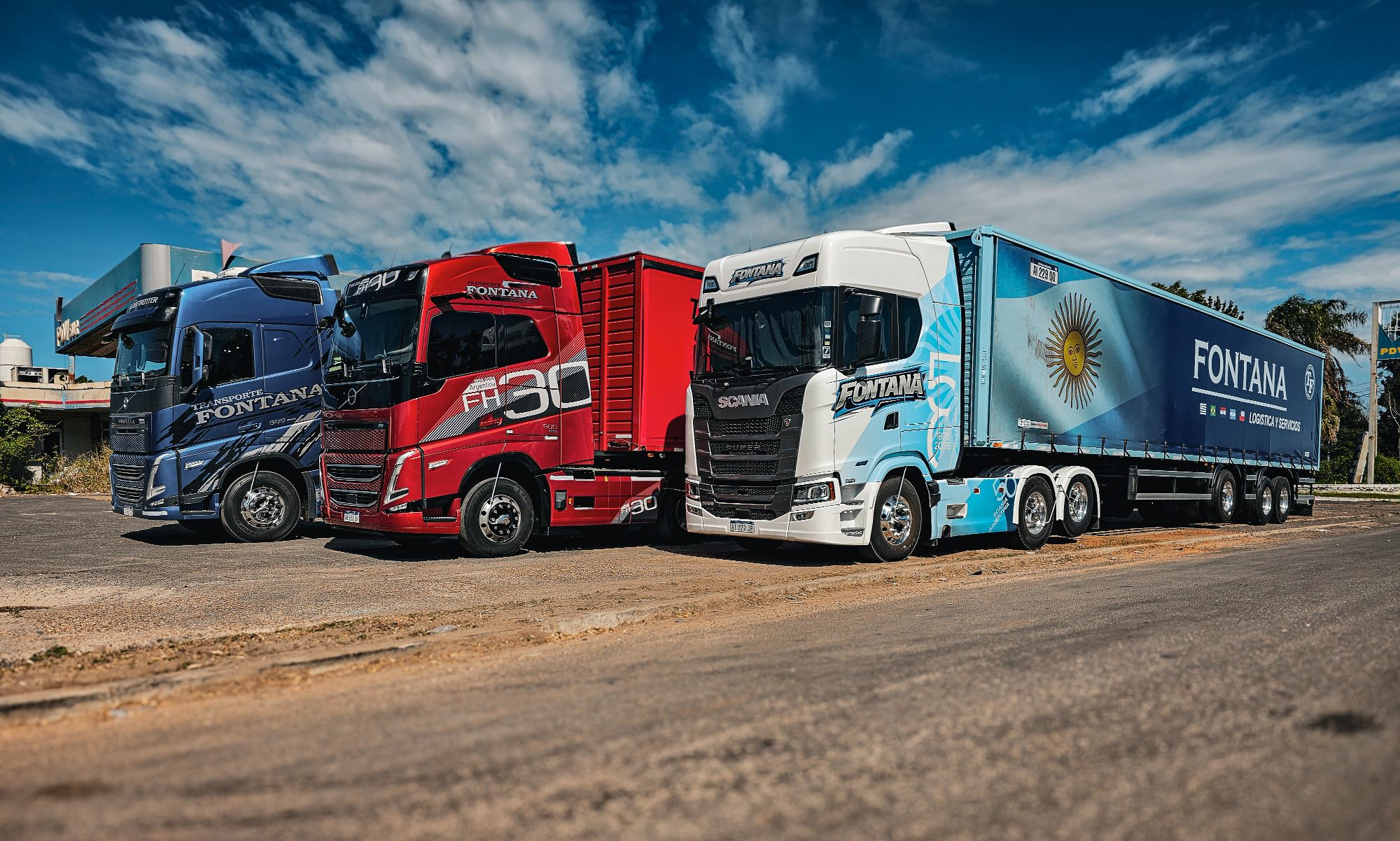 Tres camiones de la flota Fontana en fila, con la bandera argentina en el acoplado